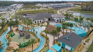 Un complexe hôtelier doté d’une piscine, de palmiers et bordé d’une route.