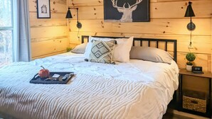 Un dormitorio acogedor con techo de madera, una cama con ropa blanca, un ventilador de techo y una decoración de cornamentas de ciervo.