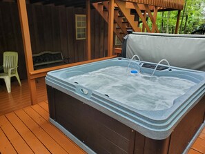 Un jacuzzi en una terraza de madera con barandilla de madera y una silla.