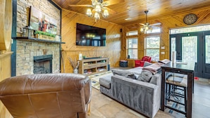 Un interior de madera con chimenea, un sofá, un televisor y un comedor.