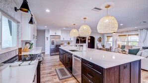 A modern kitchen with a large island, stainless steel appliances, and pendant lighting. - ⚓Cortez Cabana! Canal front home w/heated pool & boat dock!⚓ (Bradenton)
