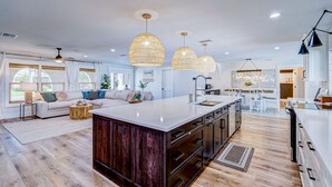 A spacious kitchen with a large island, modern pendant lights, and a view of the dining area. - ⚓Cortez Cabana! Canal front home w/heated pool & boat dock!⚓ (Bradenton)