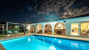 A swimming pool with a patio area, a covered outdoor kitchen, and a dining area with a view of the pool. - ⚓Cortez Cabana! Canal front home w/heated pool & boat dock!⚓ (Bradenton)