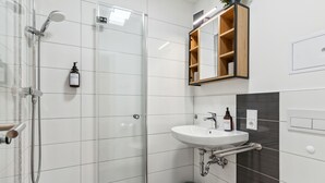 Un bagno moderno con box doccia in vetro, lavandino bianco e pensile in legno.
