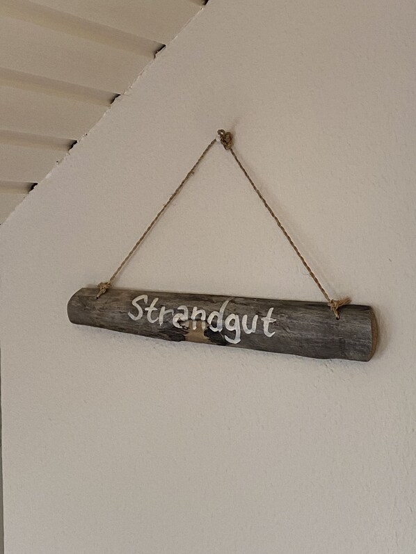 A wooden sign with the word "Strandgut" hanging on a white wall.