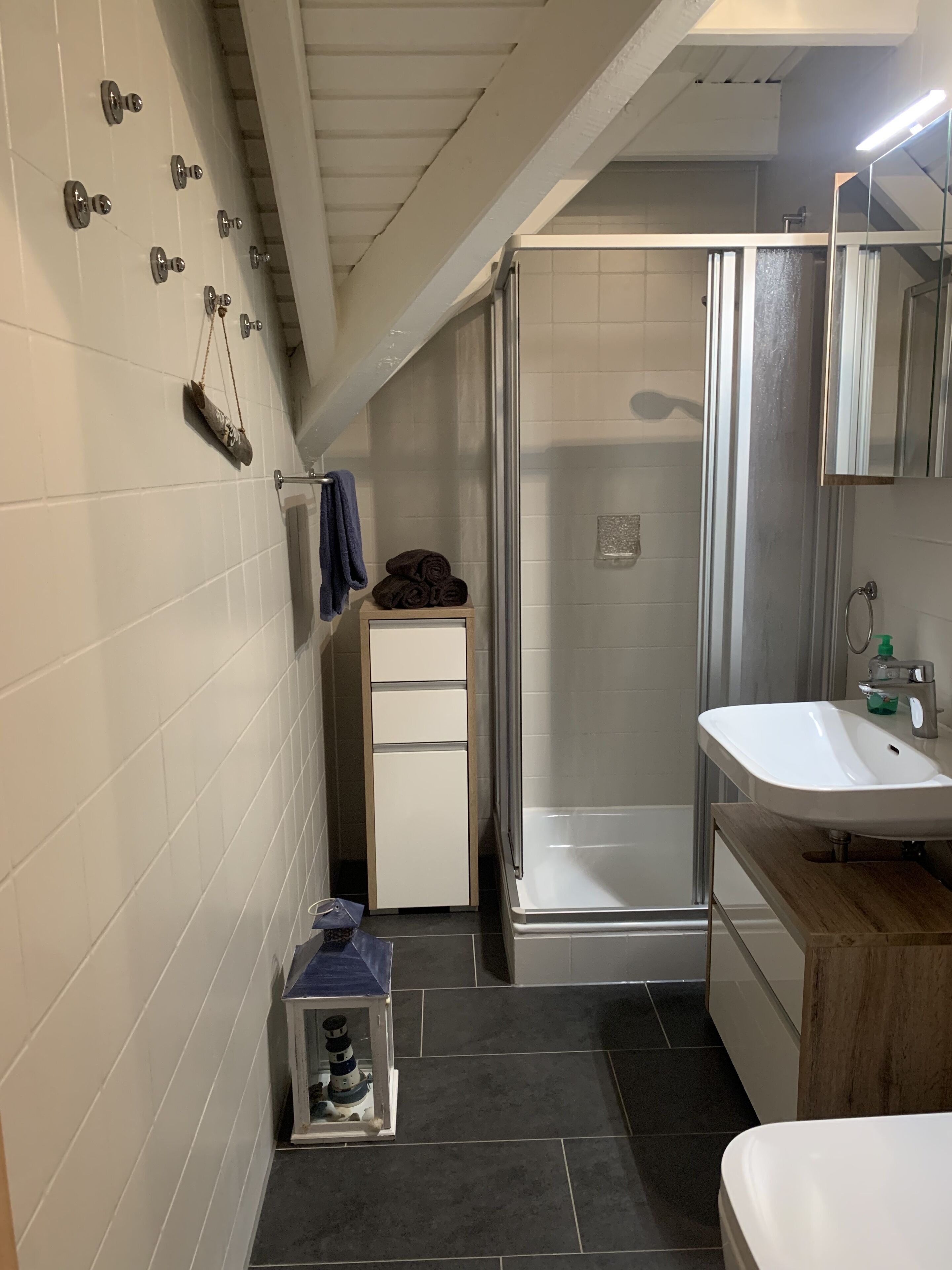 A bathroom with a shower, a sink, and a small cabinet.