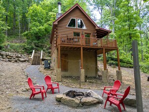 A log cabin with a balcony, surrounded by trees. -  Cozy Romantic cabin near Pigeon Forge Fireplace: Hot tub and Heart shaped tub! (Sevierville)