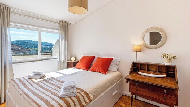Une chambre d’hôtel avec un lit, une table de chevet, une lampe, un miroir et une vue sur l’extérieur.