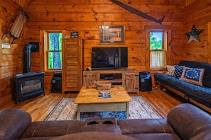 A cozy cabin interior with a wooden interior, a fireplace, a television, and a sofa. - Liberty Belle: Budget friendly near Hocking River (Logan)