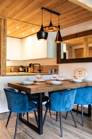 A dining area with a wooden table set for four, blue chairs, and pendant lighting. - Immodreams - Le Blue Velvet - Avoriaz (Avoriaz)