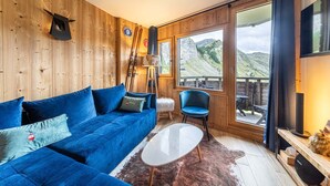 A cozy room with a blue sofa, a small white table, and a view of a mountainous landscape through large windows. - Immodreams - Le Blue Velvet - Avoriaz (Avoriaz)