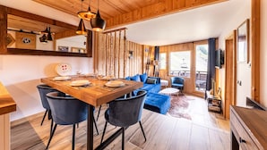 A wooden interior with a dining area, blue sofa, and a ski lift visible through the window. - Immodreams - Le Blue Velvet - Avoriaz (Avoriaz)