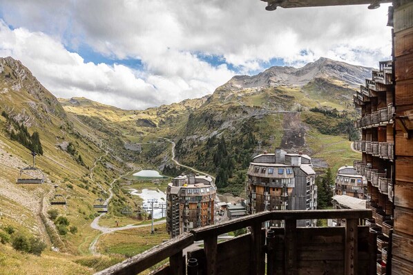 A mountain resort with wooden buildings, a ski lift, and a valley view.