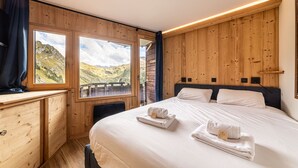 A bedroom with a large bed, wooden walls, a window with a mountain view, and a wooden desk. - Immodreams - Le Blue Velvet - Avoriaz (Avoriaz)