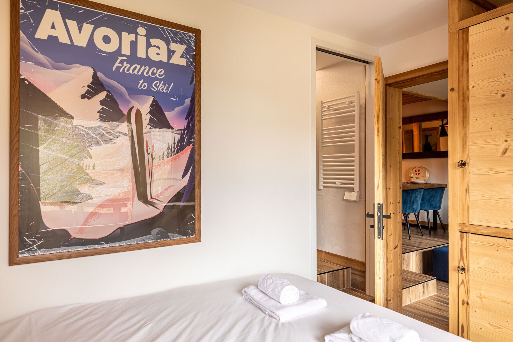 Une chambre d’hôtel avec un lit, une affiche au mur et une porte en bois donnant sur une salle de bain.
