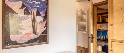 Une chambre d’hôtel avec un lit, une affiche au mur et une porte en bois donnant sur une salle de bain.