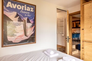 A hotel room with a bed, a poster on the wall, and a wooden door leading to a bathroom. - Immodreams - Le Blue Velvet - Avoriaz (Avoriaz)