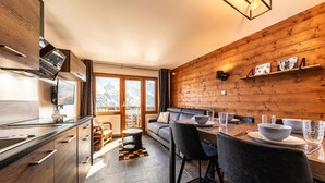 Cozinha moderna com área de jantar, paredes de madeira e vista para montanhas.