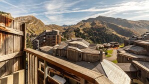 Uma aldeia rústica com edifícios de madeira tradicionais e montanhas ao fundo.
