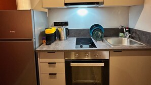 A compact kitchen with a built-in oven, a stainless steel refrigerator, and a sink.