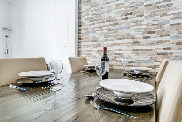 A dining table set with plates, glasses, and cutlery, with a wine bottle on the table.
