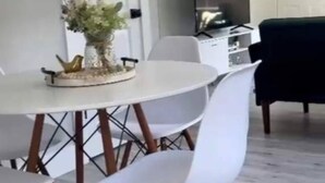 Un espace repas avec une table ronde, des chaises blanches et un élément décoratif au centre.