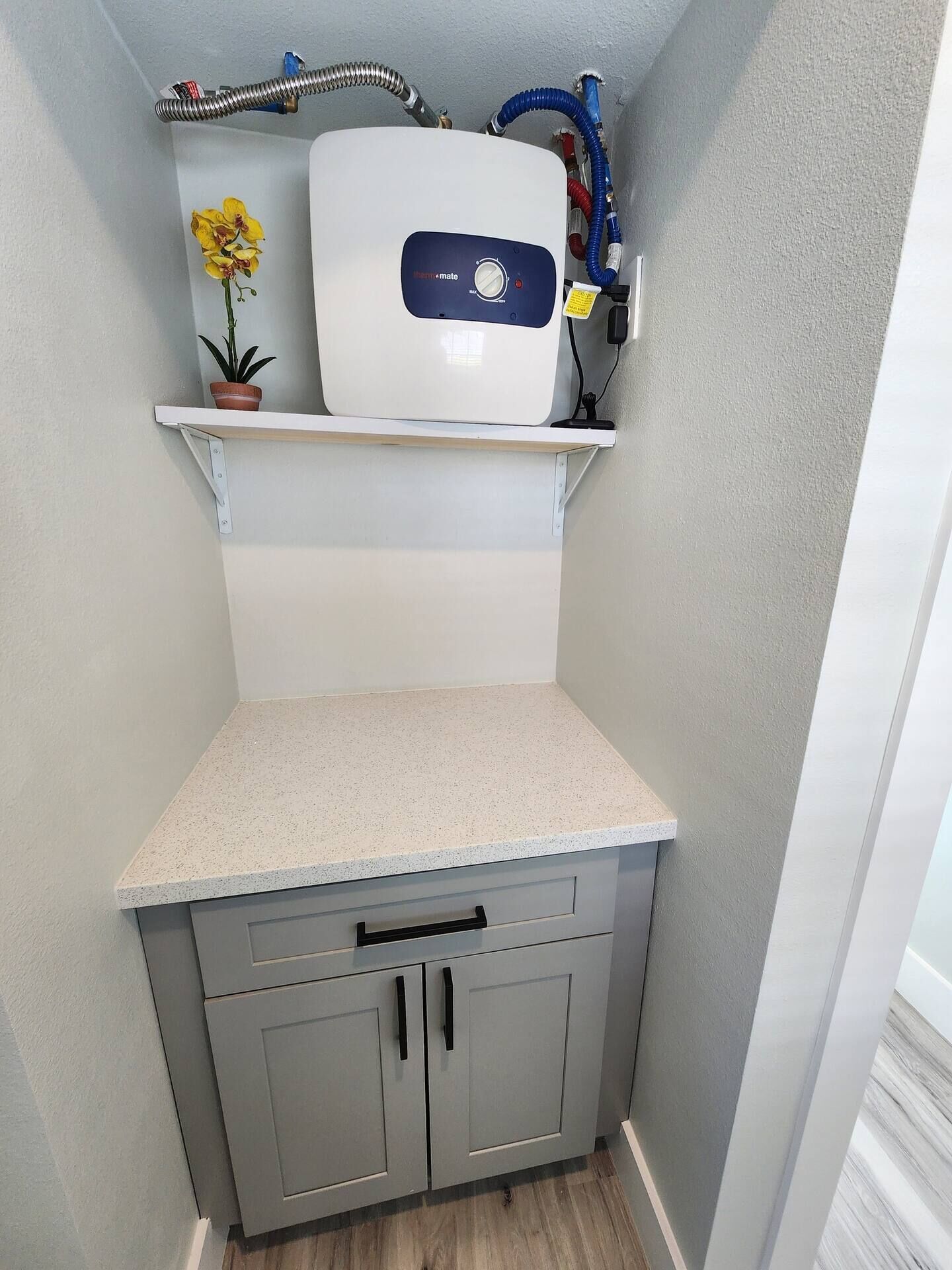 A compact kitchen with a built-in refrigerator, a small countertop, and grey cabinets.