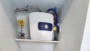 Une cuisine compacte dotée d’un réfrigérateur encastré, d’un petit plan de travail et de meubles de couleur grise.
