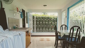 A room with a dining table, chairs, a kitchen area, and a view through a barred window. - Room-habitación Y Baño Independientes (Jimenez)