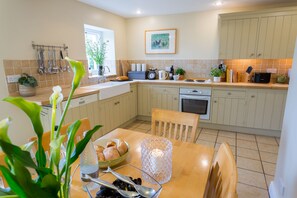 A modern kitchen with a dining table, chairs, and a variety of kitchen appliances and utensils.