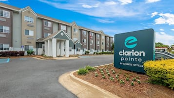 Entrada de hotel con un letrero que dice 'Clarion Pointe by Choice Hotels', un camino de acceso y un estacionamiento.