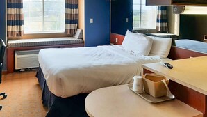 A hotel room with a bed, bedside table, and a window with curtains. - Starkville Inn and Suites (Starkville)