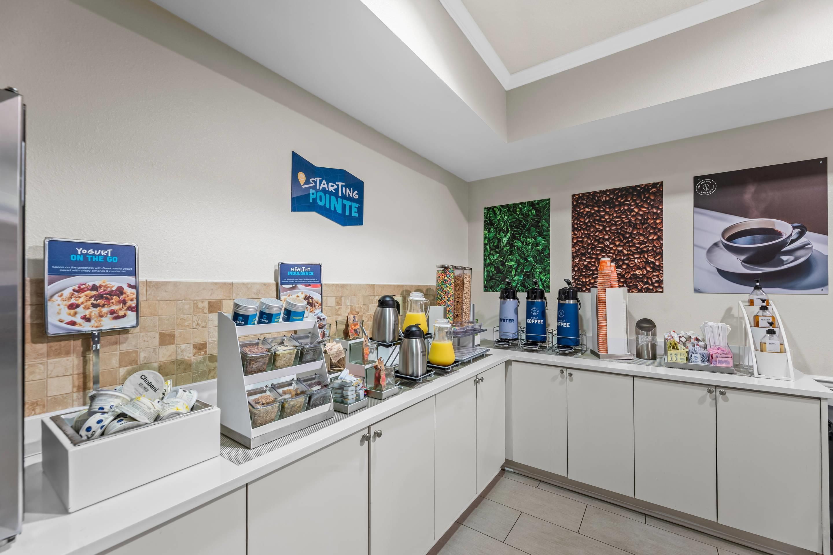 Un buffet de petit-déjeuner proposant une variété d’aliments et de boissons, notamment des yaourts, du café et des jus de fruits.