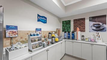 A breakfast bar with various food and drink options, including yogurt, coffee, and juice.