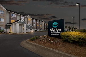 A hotel entrance with a sign for Clarion Pointe by Choice Hotels, featuring a modern building facade and a well-lit driveway.