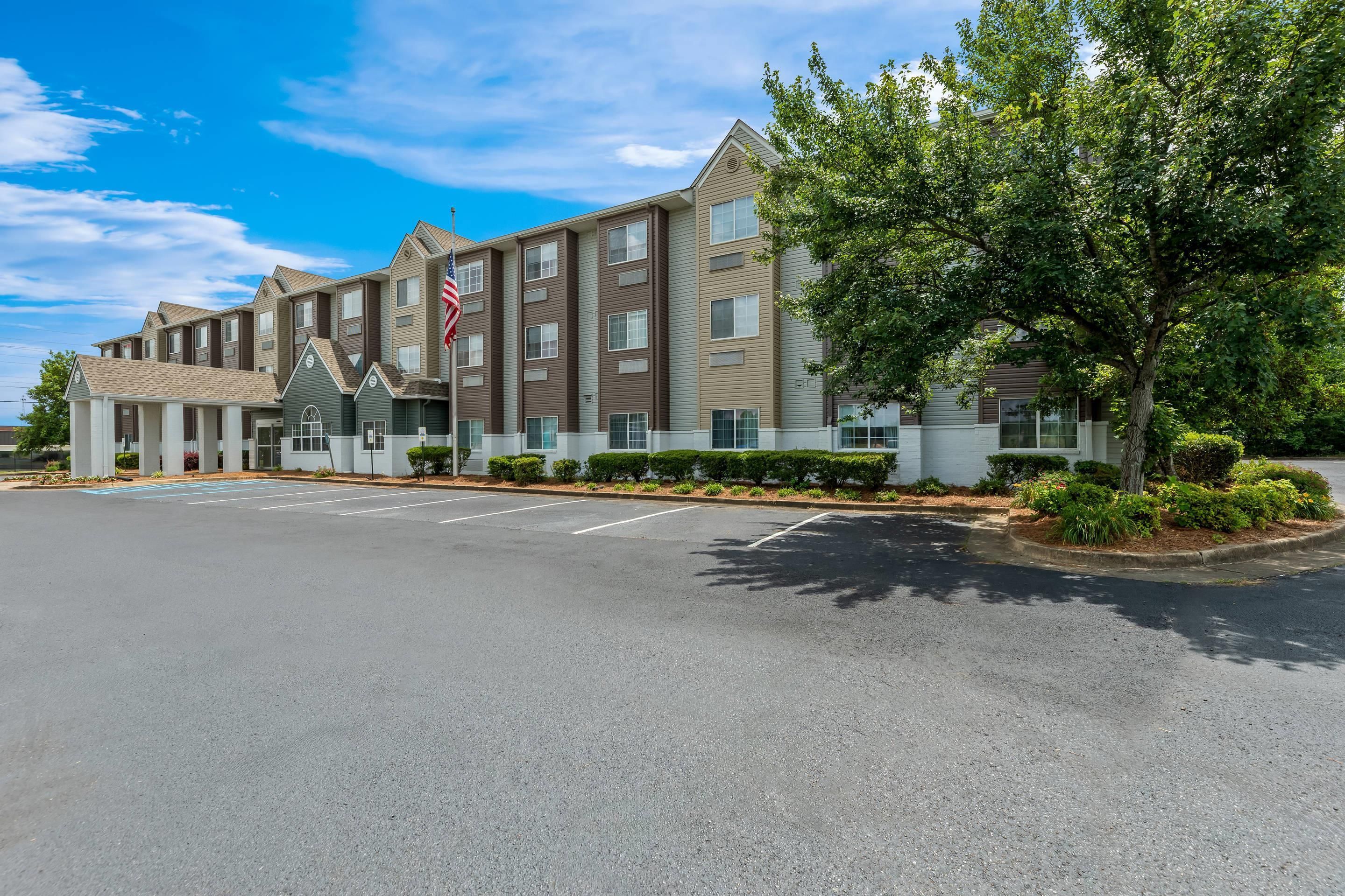 A multi-story hotel with a parking lot and a flag.