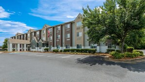 A multi-story hotel with a parking lot and a flag. - Starkville Inn and Suites (Starkville)