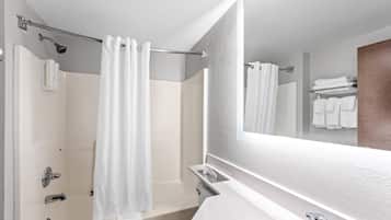 A modern bathroom with a bathtub, a toilet, and a large mirror.