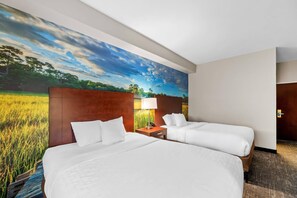 A hotel room with two beds, a nightstand, a lamp, and a large wall mural of a field and sky. - Starkville Inn and Suites (Starkville)