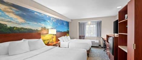 A hotel room with two beds, a desk, a TV, and a large landscape painting on the wall.
