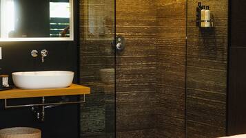 Un baño moderno con un espejo grande, un lavamanos blanco y una pared de madera con textura.
