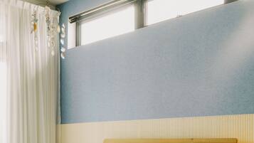 A neatly made bed with a blue blanket, a bedside lamp, and a blue rug on a wooden floor.