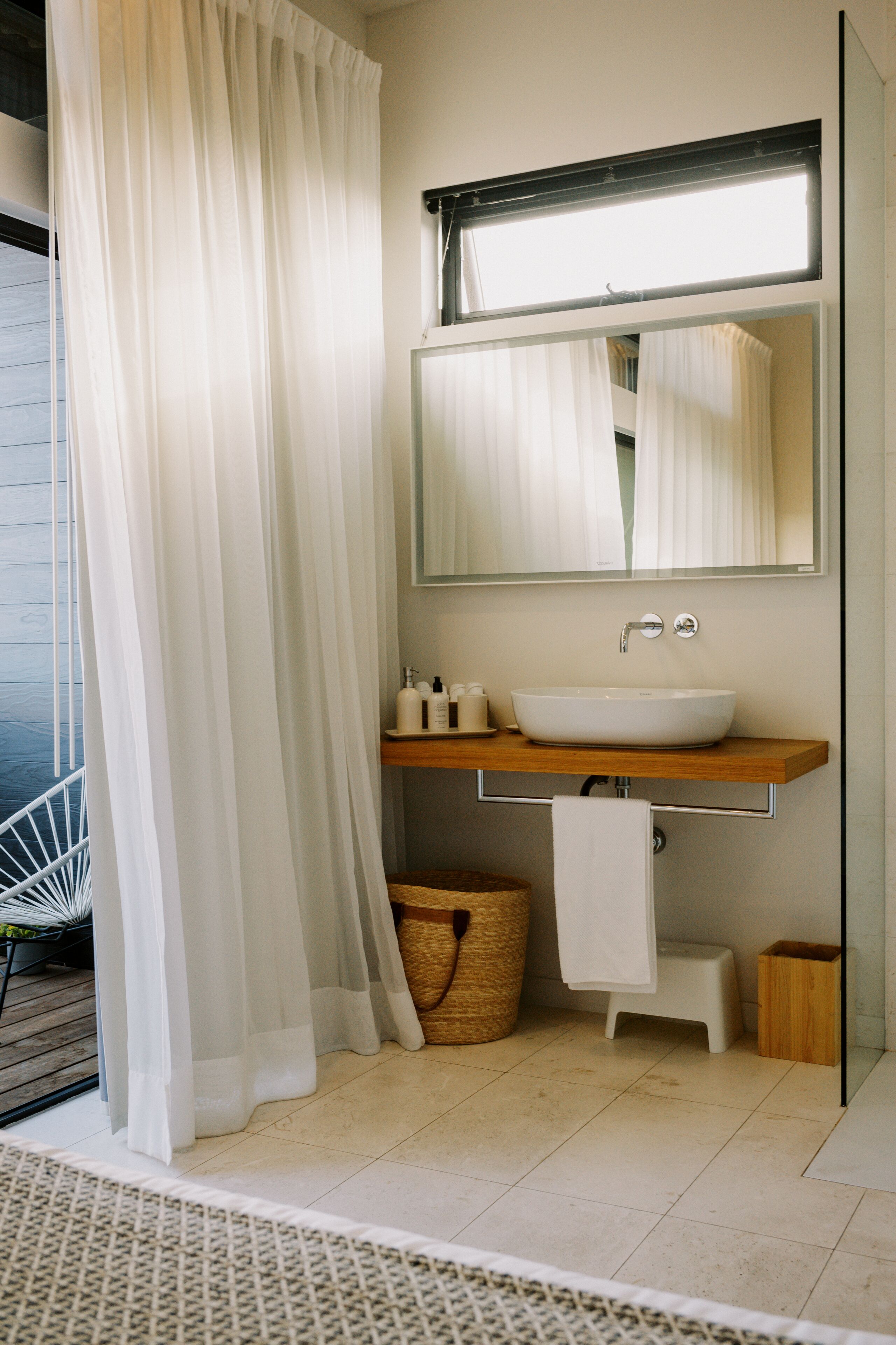 Ein modernes Badezimmer mit einem großen Spiegel, einem weißen Waschbecken und einer Holzausstattung.