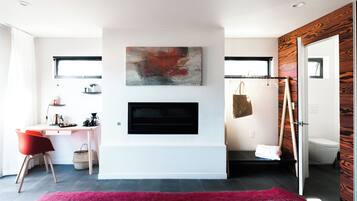 A modern room with a flat-screen TV mounted on the wall, a desk with a chair, a red rug, and a wooden wall panel.