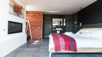 Un dormitorio moderno con una cama grande, un televisor, una pared de acento de madera, un baño con espejo y un cuadro en la pared.