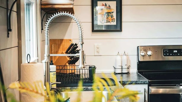 A kitchen with a stainless steel range hood, a dish rack, and a stove. - Stay Roanoke | Rustic Cabin Near McAfee Knob (Catawba)