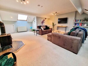 A living room with a sofa, a coffee table, a TV, a bookshelf, and a radiator.