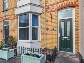 A corner building with a bay window, a green door, and a number '2' sign.
