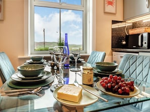 A dining table set with plates, glasses, a bottle, and a bowl of grapes.
