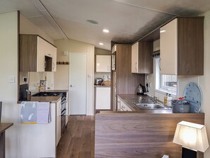 Eine moderne Küche mit Holzausstattung, einem Herd, einem Spülbecken und einem Fenster.